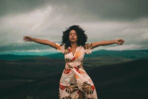 Woman in floral dress with arms outstretched.